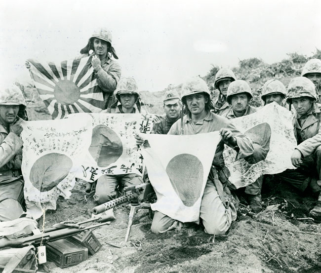 日章旗と旭日旗を持ち記念撮影する連合国軍の兵士たち